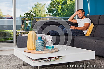 Young man texting with his phone with bored expression on his face. Stock Photo