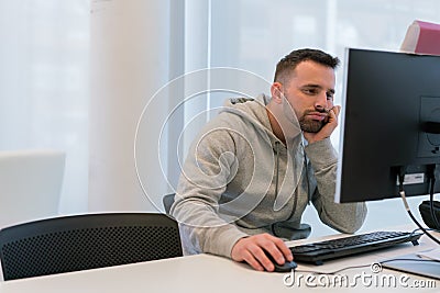 Young man tired and bored of his work in front of the computer screen Stock Photo