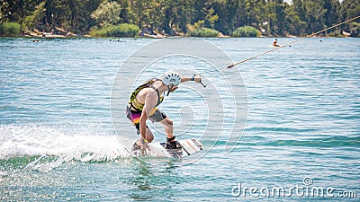 Young man touching water surface during wakeboarding Editorial Stock Photo