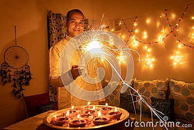 Young man in traditional dress holding the fireworks in hand with ferry lights background Stock Photo