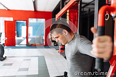 A young man trains in the gym, shakes on the gym triceps and bic Stock Photo