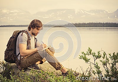 Young Man Traveler with backpack reading book Stock Photo