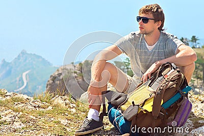 Young Man Traveler with backpack relaxing on Mountain summit rocky cliff with aerial view of Sea Stock Photo