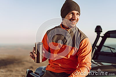 Young man traveler drinking from his thermocup while halt on a hike Stock Photo