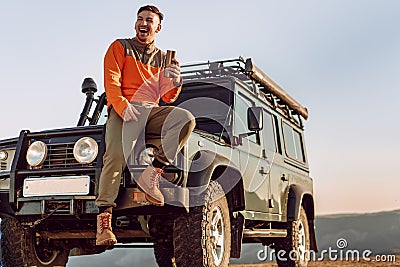 Young man traveler drinking from his thermocup while halt on a hike Stock Photo