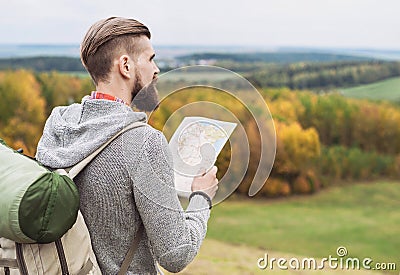 Young man traveler standing on top of the hill and looking to the map. Travel concept Stock Photo