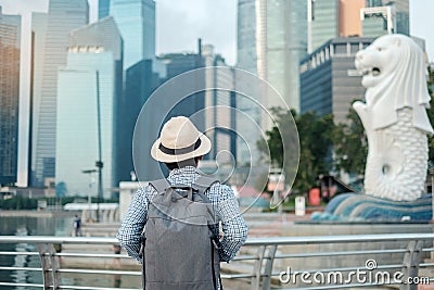 Young man traveling with backpack and hat in the morning, Solo Asian traveler visit in Singapore city downtown. landmark and Editorial Stock Photo