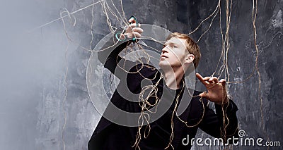 Young man tries to cut the straps with scissors. The concept of liberation from manipulation Stock Photo