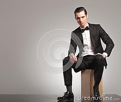 Young man in tuxedo is sitting with open coat Stock Photo