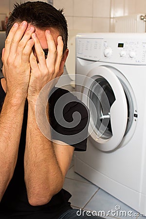 Young man unhappy with washing mashine Stock Photo