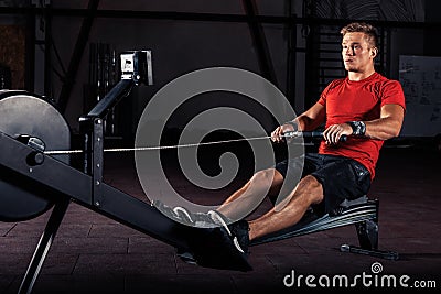 Young man using rowing machine in the gym Stock Photo