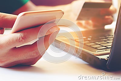 Young man using smartphone and holding credit card with laptop f Stock Photo