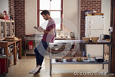 Young man using tablet computer in kitchen, full length Stock Photo
