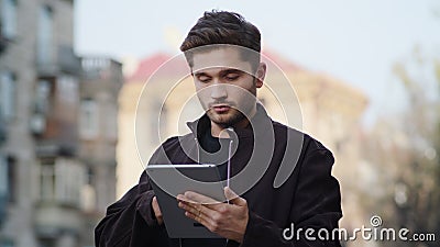 Young man using tablet outside. Hipster guy looking device screen outdoors. Stock Photo