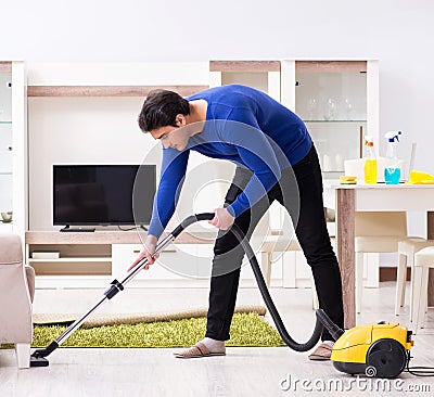 Young man vacuum cleaning his apartment Stock Photo