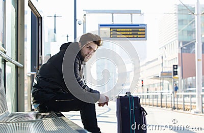 Young man waiting for train with suitcase travel bag Stock Photo