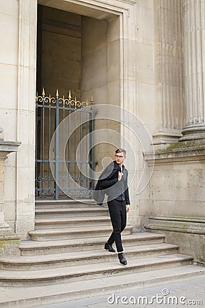 Young man walking on concrete stairs, metal gate in background. Stock Photo