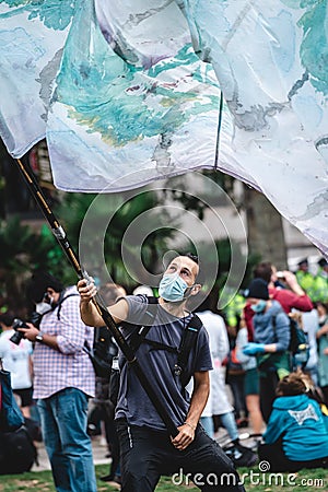 Young man waving giant flag at Extinction Rebellion Protest at Parliament square Editorial Stock Photo