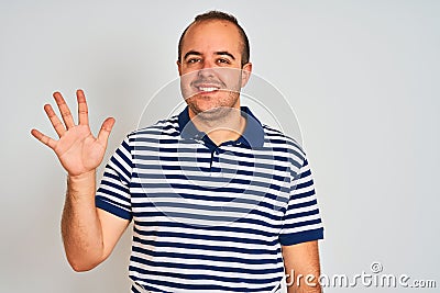 Young man wearing casual striped polo standing over isolated white background showing and pointing up with fingers number five Stock Photo