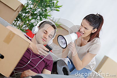 Young man wearing headphones oblivious to girlfriend shouting through loudhailer Stock Photo