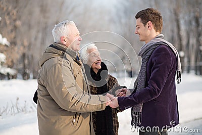 Young man wearing a scarf greets an elderly couple Stock Photo