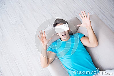 The young man wearing vr glasses relaxing on couch sofa Stock Photo