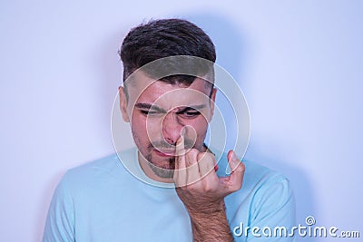 Young man on white background sticking his finger up his nose and pulling out a booger. The man is a pig. Concept various Stock Photo