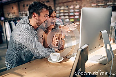 Young man and woman colleagues excited about great solution for a project work, looking at screen in a creative modern office Stock Photo