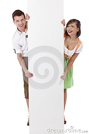 Young man and woman with dirndl holding ad space Stock Photo