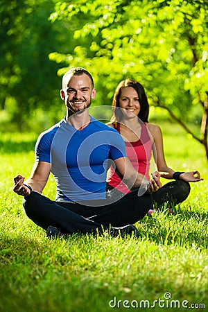 Young man and woman doing yoga in the sunny summer park Stock Photo