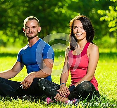 Young man and woman doing yoga in the sunny summer park Stock Photo