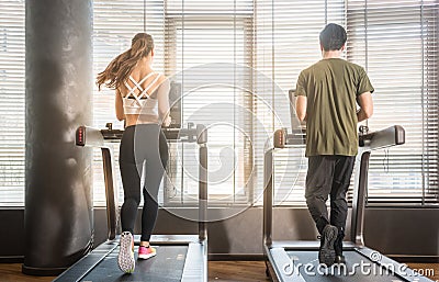 Young man and woman running on treadmills during workout Stock Photo