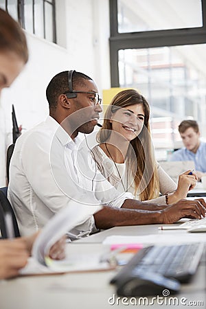 Young man and woman working in an open plan office, vertical Stock Photo