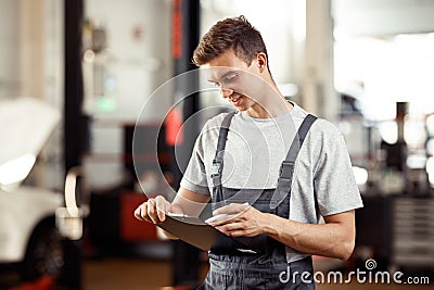 A young man working at a car repair service is filling in a form Stock Photo