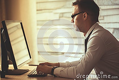 young man working from home on computer, manager at his workplace using technology, flare light.Male hands typing on laptop Stock Photo