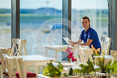 Young man working with laptop at airport cafe w Stock Photo