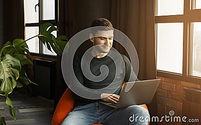 Young Man Working On Laptop Browsing Internet Sitting At Home Stock Photo