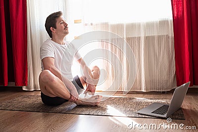 Young man working out, doing butterfly yoga pose at the living room at home. Stock Photo