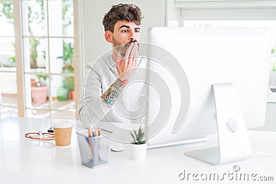 Young man working using computer cover mouth with hand shocked with shame for mistake, expression of fear, scared in silence, Stock Photo