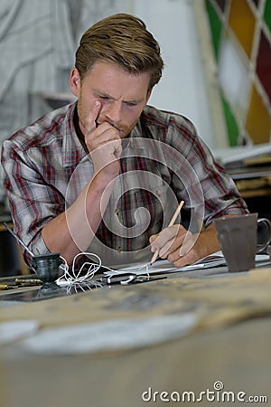 young man in workshopwriting obligations in notes Stock Photo