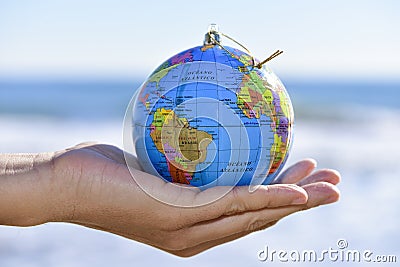 Young man with a world globe as a christmas ball in his hand Stock Photo