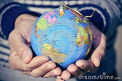 Young man with a world globe as a christmas ball in his hands Stock Photo