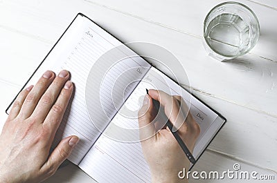 Man hands writing notes to the notebook on wooden table in home office Stock Photo