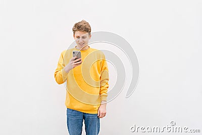 Young man writing sms standing by concrete wall. copy space Stock Photo