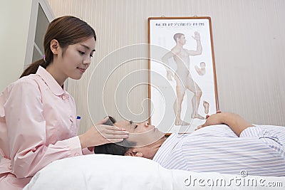 Young Masseuse Giving Chinese Traditional Medical Facial Massage Stock Photo