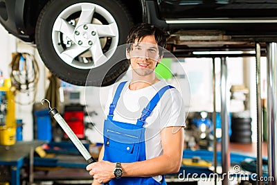 Young mechanic in blue overall working on car Stock Photo