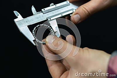 A young mechanic makes measurements of the bearing with a special tool. The locksmith has a caliper bearing in his hand. Repair of Stock Photo