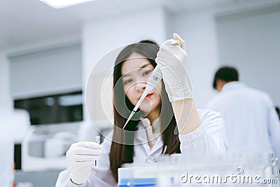 Young female scientist using auto pipette to transfer sample Stock Photo