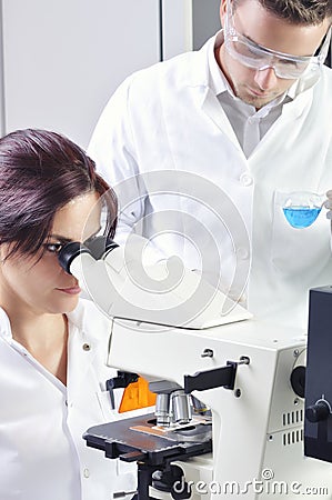 Young medical scientists studying new substance or virus in microscope Stock Photo