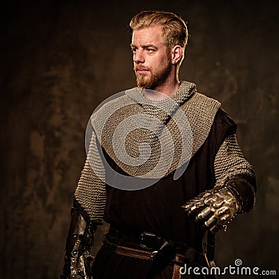 Young medieval knight posing on dark background. Stock Photo